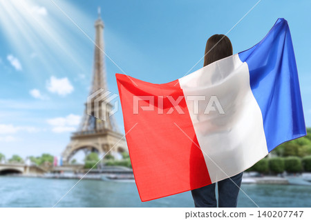 Woman waves French flag by Eiffel Tower. Travel and cultural experience concept Woman waves French flag by Eiffel Tower. Travel and cultural experience concept 140207747