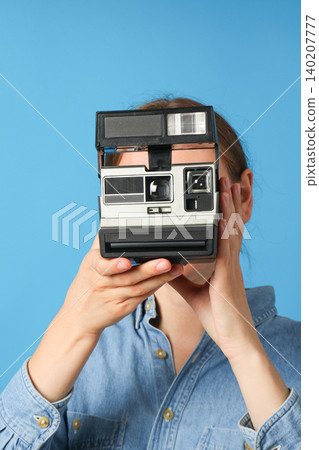 Person aims a retro camera at the viewer with blue backdrop Person aims a retro camera at the viewer with blue backdrop 140207777