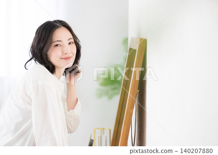 A woman's lifestyle: styling her hair and grooming herself in front of a mirror; upper body, looking directly at the camera. A woman's lifestyle: styling her hair and grooming herself in front of a mirror; upper body, looking directly at the camera. 140207880