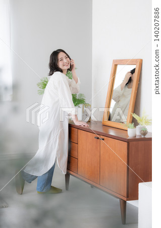 女性的生活方式:在鏡子前梳妝打扮,直視鏡頭。 女性的生活方式:在鏡子前梳妝打扮,直視鏡頭。 140207886