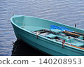 Blue rowboat with wooden oars floats on calm blue water at a lakeside. Leisure craft with seats and oars suggests summer holidays and peaceful relaxation. 140208953