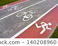 Separated bike and running lanes with painted bicycle and runner symbols on a paved path. Promotes cycling, pedestrian fitness and sustainable transport, linked to World Bicycle Day and Car Free Day. 140208960