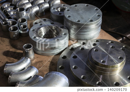 Parallel stainless steel pipe components such as flanges and elbows. 140209170