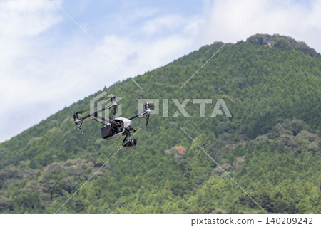 專業無人機在鬱鬱蔥蔥的青山背景下飛行的空拍畫面。 專業無人機在鬱鬱蔥蔥的青山背景下飛行的空拍畫面。 140209242