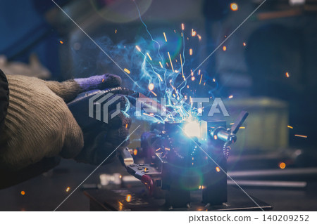 A close-up shot of a welding torch being used to weld metal, with pale blue sparks flying everywhere. A close-up shot of a welding torch being used to weld metal, with pale blue sparks flying everywhere. 140209252