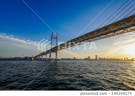 夕陽西下,海灣大橋和港口未來映照在陽光下。 夕陽西下,海灣大橋和港口未來映照在陽光下。 140209275