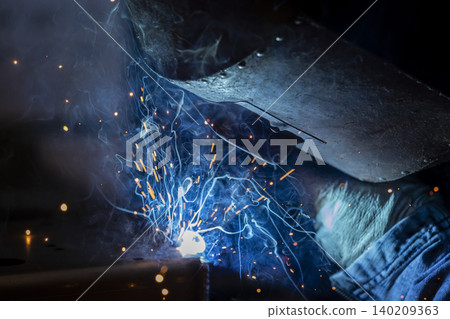 A close-up of the blue flames and sparks radiating outwards at the moment of welding. A close-up of the blue flames and sparks radiating outwards at the moment of welding. 140209363