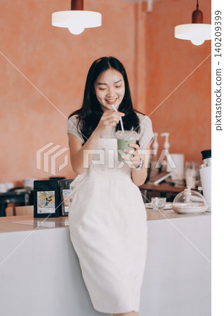 Young woman drinking iced coffee outside a chocolate shop Young woman drinking iced coffee outside a chocolate shop 140209399