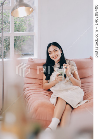 Young woman drinking iced coffee outside a chocolate shop Young woman drinking iced coffee outside a chocolate shop 140209400