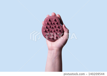 Hair pink scalp massager in woman hand on the pink background isolated. Image with copy space. Mock up for design and banner 140209544