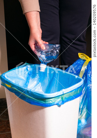 Woman putting used plastic bottle in waste bin, separate waste collection and recycling concept. High quality photo 140209576