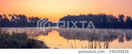 Magical dawn over the lake with a beautiful reflection on the water. Serene lake in the early morning. Nature landscape Magical dawn over the lake with a beautiful reflection on the water. Serene lake in the early morning. Nature landscape 140209856