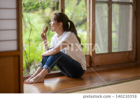 A woman eating dorayaki in an old Japanese house 140210358