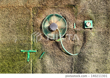 Secret door concealed by grass with a small ventilation fan, hidden in a natural outdoor setting Secret door concealed by grass with a small ventilation fan, hidden in a natural outdoor setting 140211301