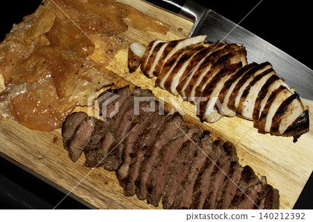 Close up of sliced meat chicken steak choizo platter on a wooden chopping board 140212392