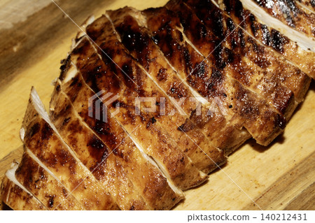 Close up of sliced roasted and glazed chicken breast on a wooden chopping board Close up of sliced roasted and glazed chicken breast on a wooden chopping board 140212431