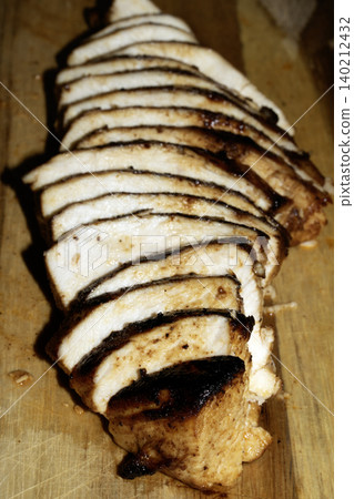 Close up of sliced roasted and glazed chicken breast on a wooden chopping board Close up of sliced roasted and glazed chicken breast on a wooden chopping board 140212432