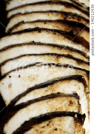 Close up of sliced roasted and glazed chicken breast on a wooden chopping board Close up of sliced roasted and glazed chicken breast on a wooden chopping board 140212436