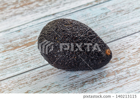 Single ripe Hass avocado on weathered blue wooden planks Single ripe Hass avocado on weathered blue wooden planks 140213115
