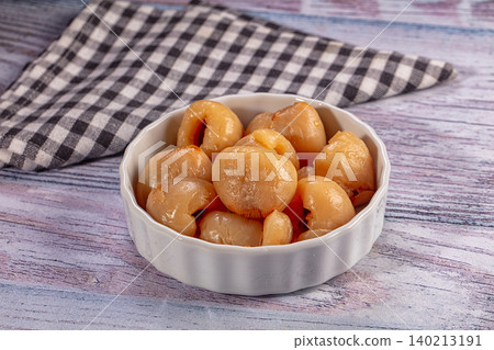Peeled longan fruit in white bowl on rustic wooden table with checkered napkin 140213191