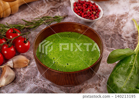 Green spinach cream soup in wooden bowl with fresh tomatoes, garlic, rosemary, and pink peppercorns on marble table Green spinach cream soup in wooden bowl with fresh tomatoes, garlic, rosemary, and pink peppercorns on marble table 140213195