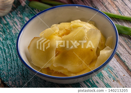 Sliced pickled ginger in bowl with green onions on rustic wooden table Sliced pickled ginger in bowl with green onions on rustic wooden table 140213205