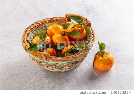 Fresh sweet juicy tangerine heap in wicker basket on light background Fresh sweet juicy tangerine heap in wicker basket on light background 140213254