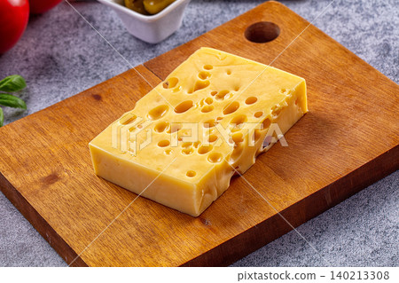 Block of Swiss cheese with holes on wooden cutting board Block of Swiss cheese with holes on wooden cutting board 140213308