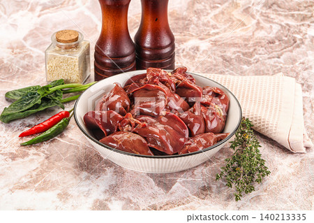 Raw chicken liver in bowl with spices and vegetables on marble table 140213335