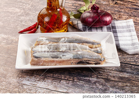 Marinated pickled salted herring fillet with red onion and chili pepper on wooden table Marinated pickled salted herring fillet with red onion and chili pepper on wooden table 140213365