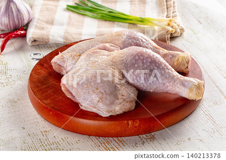 Raw whole chicken legs on wooden cutting board with garlic and spring onions Raw whole chicken legs on wooden cutting board with garlic and spring onions 140213378