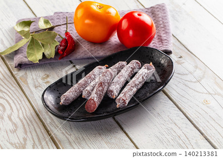 Dry salami mini sausage snack with tomatoes and spices on wooden table Dry salami mini sausage snack with tomatoes and spices on wooden table 140213381