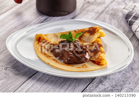 Folded crepe with chocolate spread and mint leaf on white plate Folded crepe with chocolate spread and mint leaf on white plate 140213390