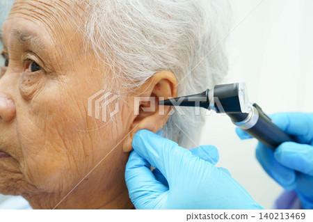 Otolaryngologist or ENT physician doctor examining senior patient ear with otoscope, hearing loss problem. Otolaryngologist or ENT physician doctor examining senior patient ear with otoscope, hearing loss problem. 140213469