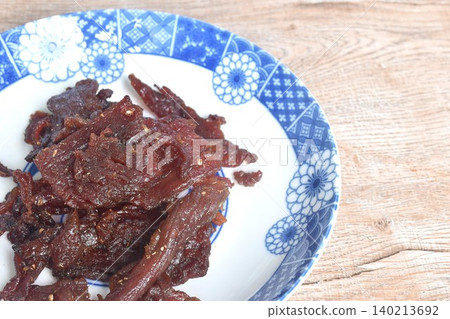 salty and sweet dry fried slice beef meat jerky fermenting in sesame oil and pepper on plate salty and sweet dry fried slice beef meat jerky fermenting in sesame oil and pepper on plate 140213692