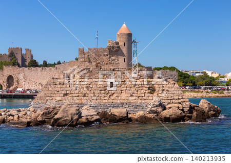 Stone lighthouse tower and medieval harbor walls in Rhodes on sunny clear summer day Stone lighthouse tower and medieval harbor walls in Rhodes on sunny clear summer day 140213935