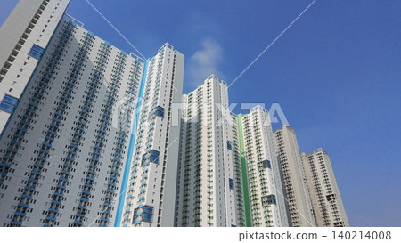 Low-angle view of modern high-rise residential apartment buildings against a blue sky 140214008