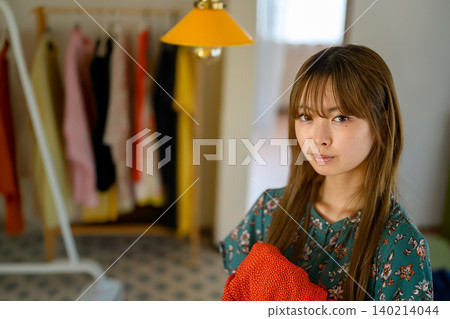 A woman choosing clothes in her room A woman choosing clothes in her room 140214044