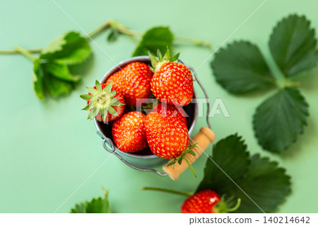 Fresh strawberries spilling from metal bucket on green background Fresh strawberries spilling from metal bucket on green background 140214642