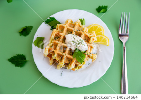 savory zucchini waffles with sour cream and fresh herbs on plate savory zucchini waffles with sour cream and fresh herbs on plate 140214664