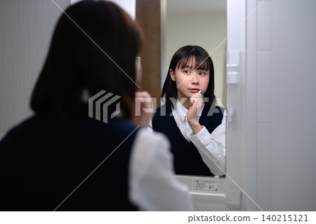 Woman brushing her teeth in front of the mirror Woman brushing her teeth in front of the mirror 140215121
