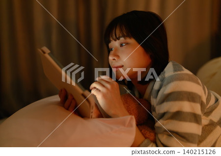 一名婦女在床上的看一種片劑 140215126
