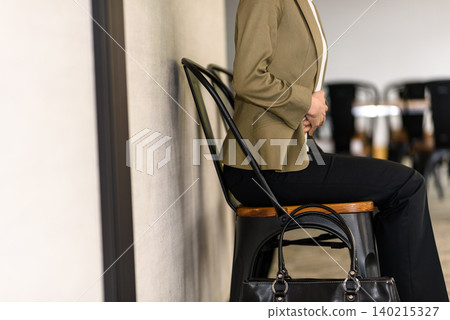 A woman is sitting in a chair and holding her stomach. A woman is sitting in a chair and holding her stomach. 140215327