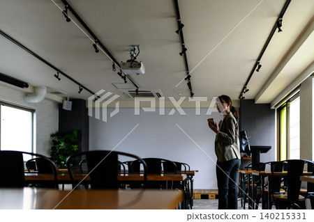 A woman looking at her smartphone in a conference room. A woman looking at her smartphone in a conference room. 140215331