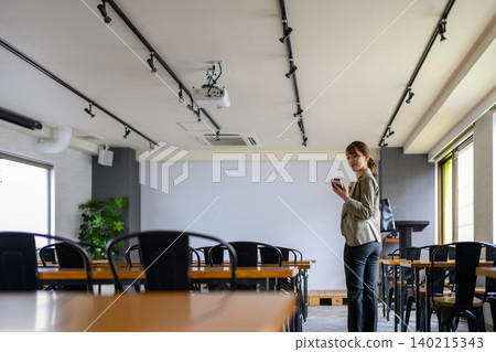 A woman looking at her smartphone in a conference room. A woman looking at her smartphone in a conference room. 140215343