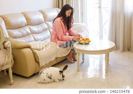 Brunette woman with domestic bunny pet at home 140215476