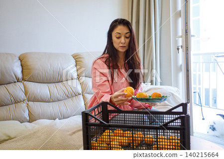 Happy woman eating tangerines at home 140215664