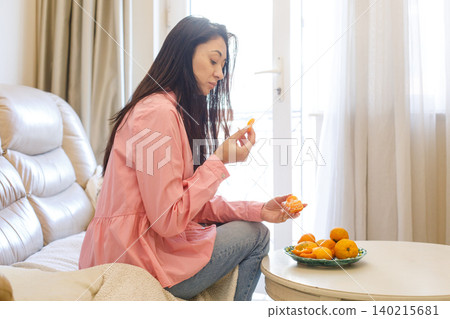 Portrait of woman eating tangerines at home Portrait of woman eating tangerines at home 140215681