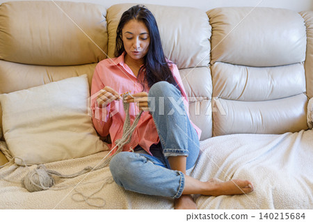 Indoor portrait of brunette woman knitting wool using needle at home Indoor portrait of brunette woman knitting wool using needle at home 140215684