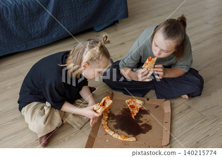 Top view of young children sitting on floor in living room and eating pizza at home Top view of young children sitting on floor in living room and eating pizza at home 140215774